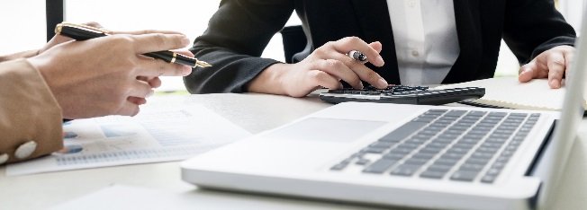 Two people working at a desk with a laptop and a calculator